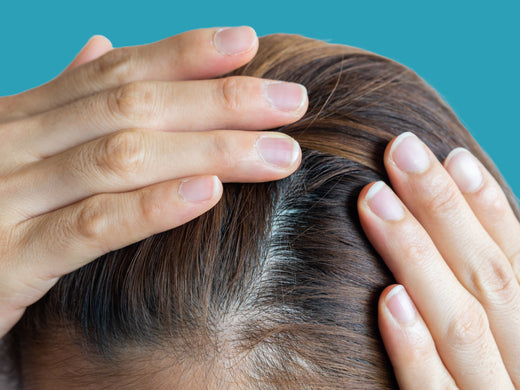 Person looking closely at their hair. Does iron deficiency have a connection to hair loss?